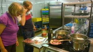  Magdalena och Mats studerar receptet till lamm "Osso Bucco" gremolata. Bogsteken fräser redan i stekpannan.